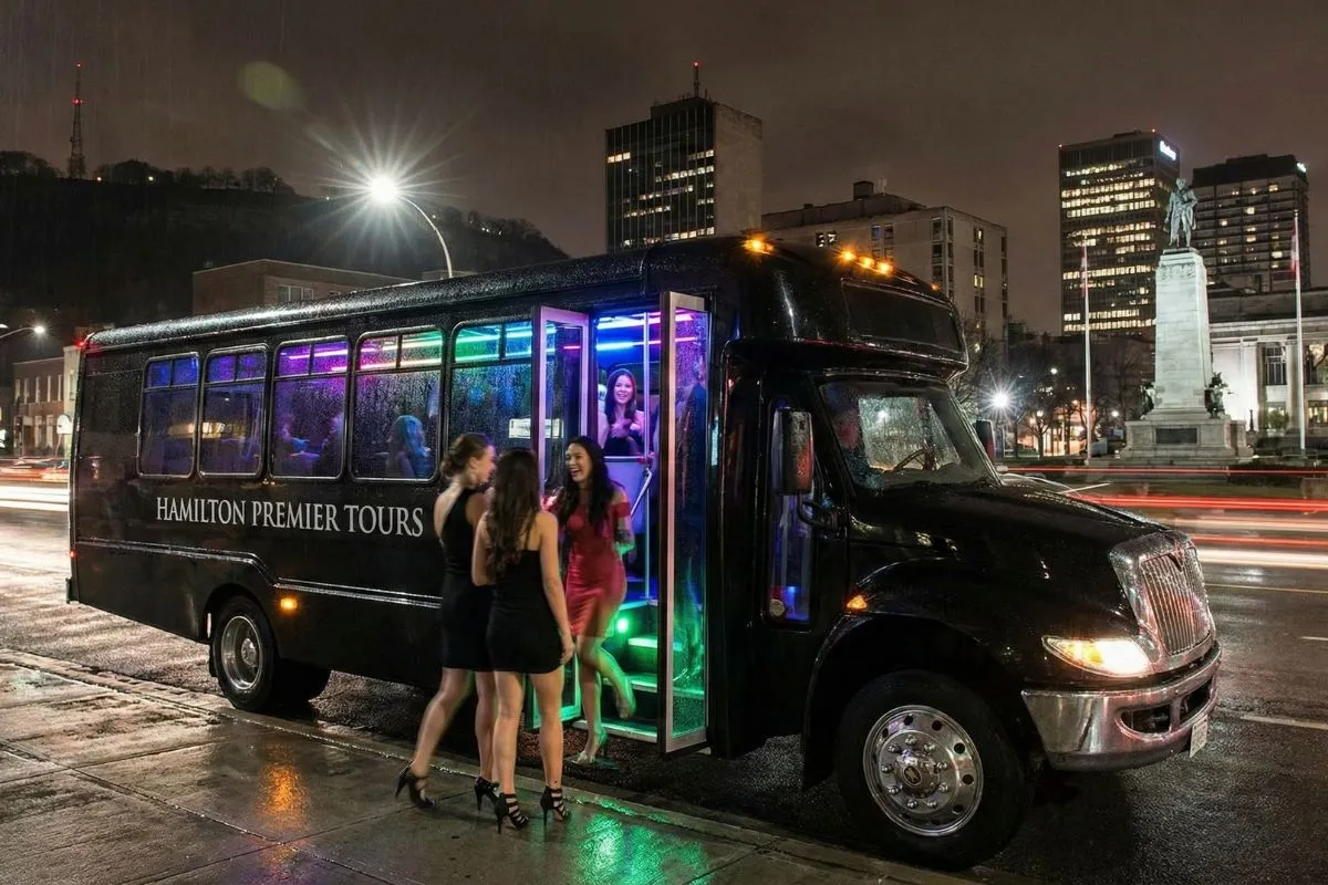 Luxury party bus rental Hamilton with LED lighting and group boarding at night.
